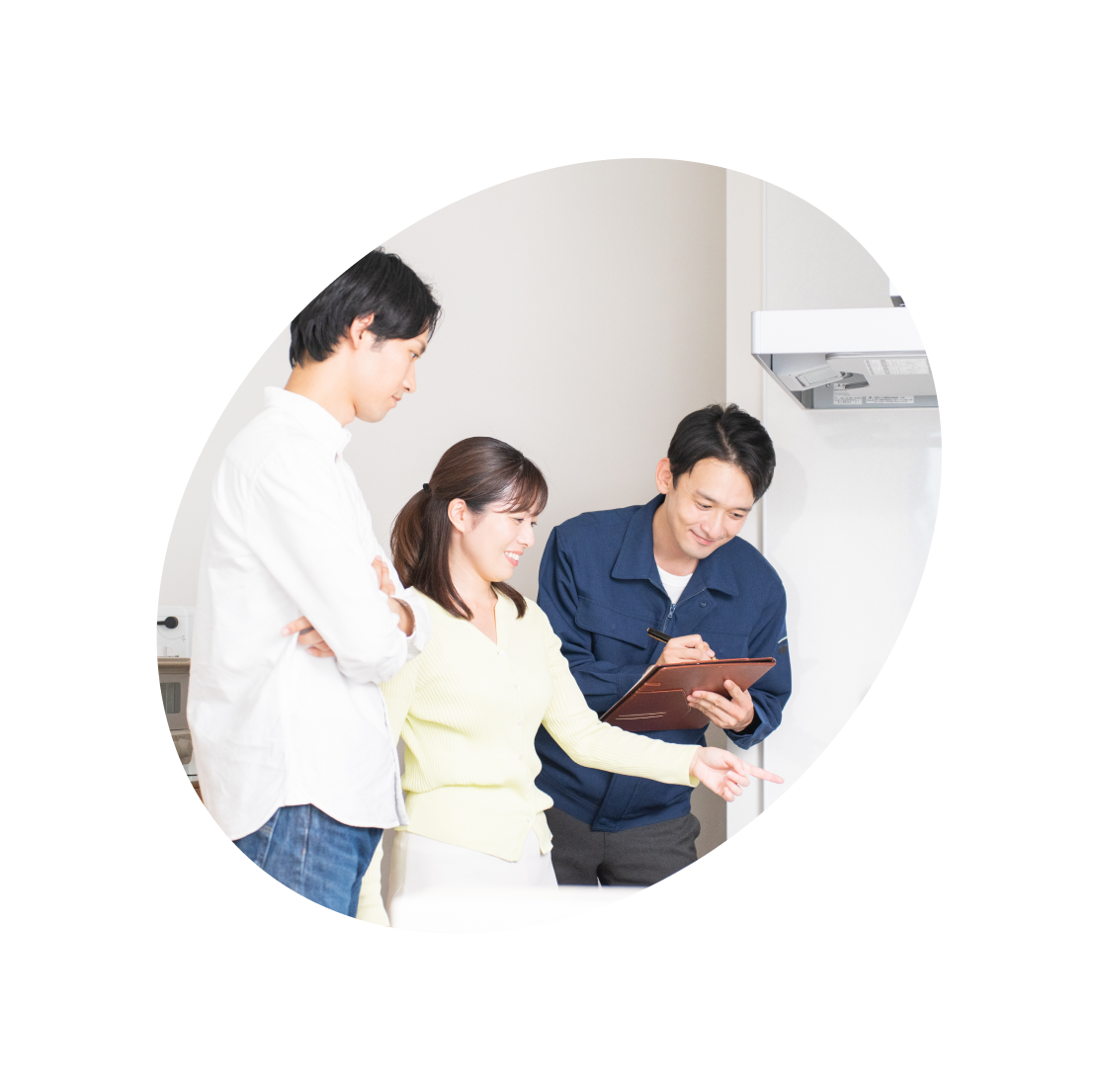 キッチンで設備点検の説明を受ける夫婦と作業員